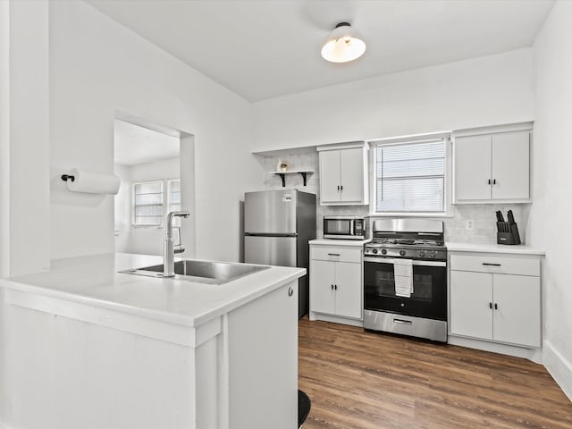 kitchen featuring appliances with stainless steel finishes, white cabinetry, tasteful backsplash, sink, and kitchen peninsula