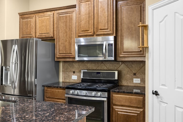 kitchen featuring backsplash, dark stone counters, and appliances with stainless steel finishes