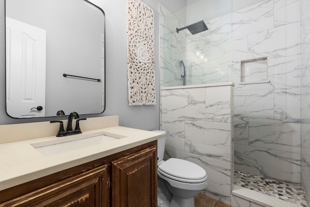 bathroom featuring tiled shower, vanity, and toilet