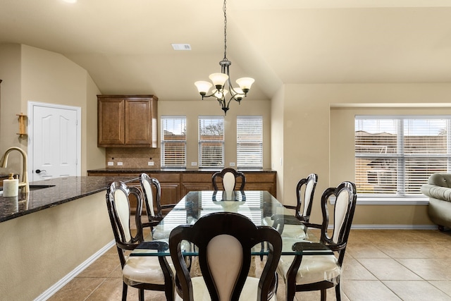 tiled dining area with sink, an inviting chandelier, and vaulted ceiling