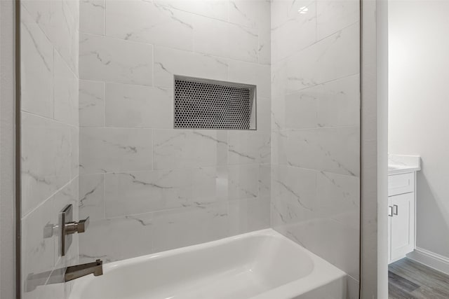 bathroom featuring tiled shower / bath combo, wood-type flooring, and vanity