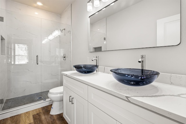 bathroom featuring hardwood / wood-style floors, toilet, walk in shower, and vanity