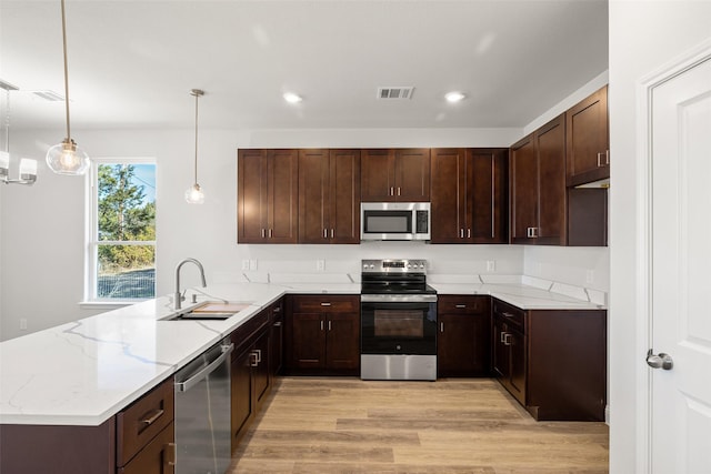 kitchen featuring light hardwood / wood-style floors, sink, kitchen peninsula, pendant lighting, and stainless steel appliances