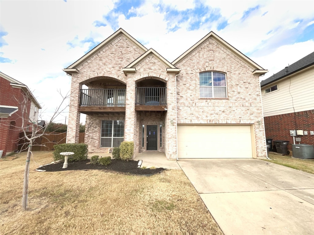 view of front of home with a garage, a balcony, a front yard, and central AC unit