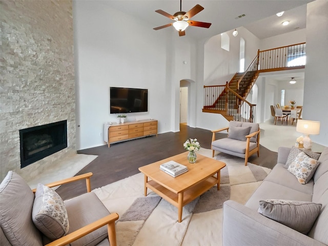 unfurnished living room with a high ceiling, ceiling fan, dark hardwood / wood-style flooring, and a fireplace