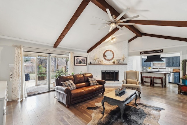 living room featuring a brick fireplace, dark hardwood / wood-style flooring, lofted ceiling with beams, and ceiling fan