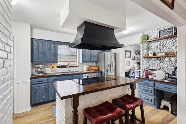 kitchen featuring sink, blue cabinetry, island range hood, and butcher block counters