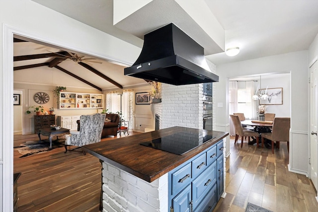 kitchen with blue cabinetry, lofted ceiling with beams, island exhaust hood, black electric cooktop, and wood counters