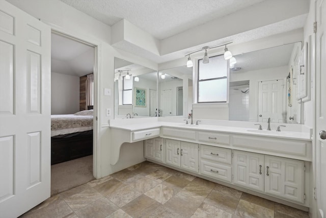 bathroom with a textured ceiling, vanity, and a healthy amount of sunlight