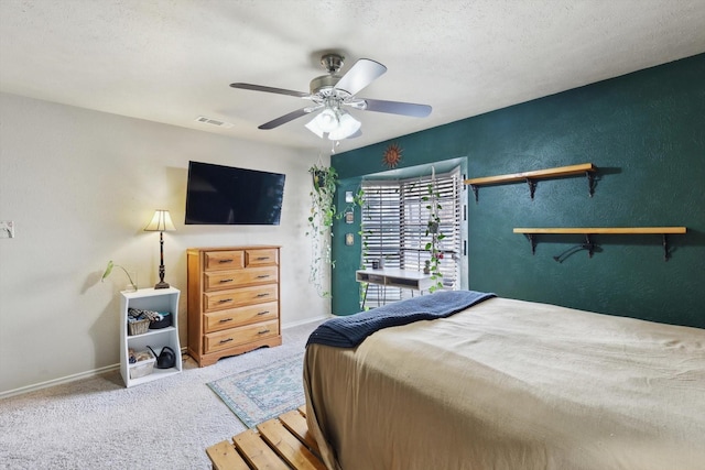 carpeted bedroom featuring ceiling fan and a textured ceiling