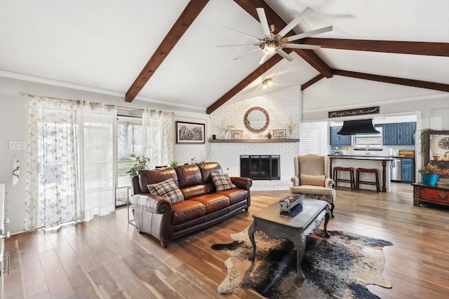 living room featuring a fireplace, wood-type flooring, ceiling fan, and vaulted ceiling with beams