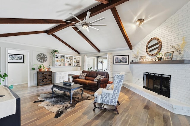 living room featuring ceiling fan, wood-type flooring, a fireplace, and lofted ceiling with beams