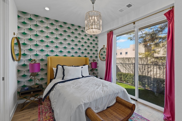 bedroom with light hardwood / wood-style flooring, access to outside, and an inviting chandelier