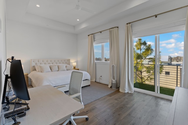 bedroom featuring wood-type flooring, a tray ceiling, access to outside, and ceiling fan