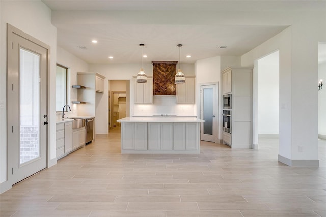 kitchen with pendant lighting, appliances with stainless steel finishes, a center island, decorative backsplash, and light wood-type flooring