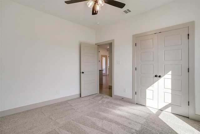 unfurnished bedroom with ceiling fan, light colored carpet, and a closet