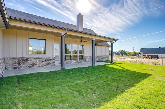 rear view of house with ceiling fan, a patio area, and a lawn