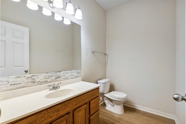 bathroom with tasteful backsplash, vanity, wood-type flooring, and toilet