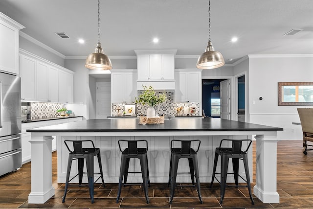 kitchen featuring a kitchen bar, a spacious island, white cabinets, and stainless steel refrigerator