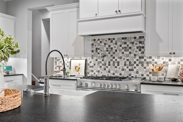 kitchen with white cabinets, high end range, decorative backsplash, and sink