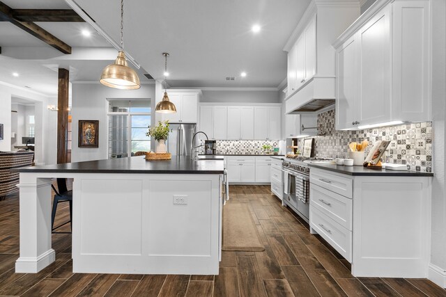 kitchen with hanging light fixtures, appliances with stainless steel finishes, sink, white cabinetry, and a kitchen island with sink