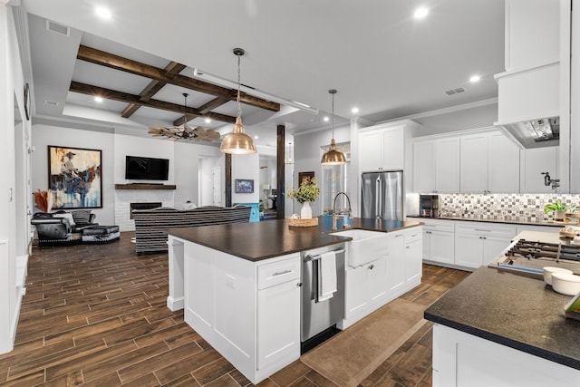 kitchen with an island with sink, white cabinets, tasteful backsplash, and appliances with stainless steel finishes