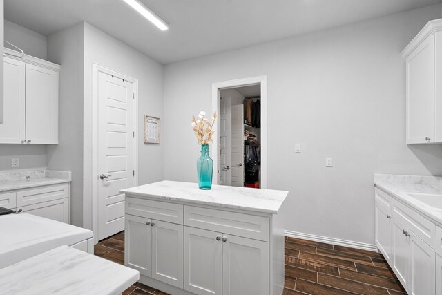 kitchen with white cabinets, light stone counters, and sink