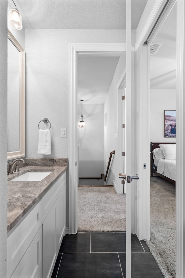 bathroom with a textured ceiling, tile patterned flooring, and vanity