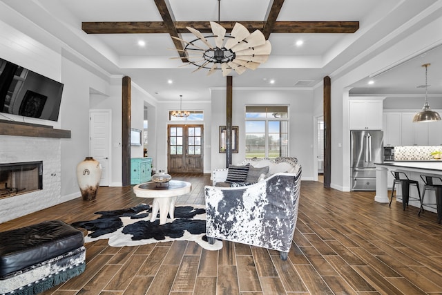 living room featuring a large fireplace, ornamental molding, and an inviting chandelier