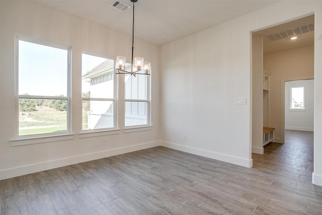 unfurnished dining area featuring a chandelier and light hardwood / wood-style floors