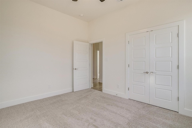 unfurnished bedroom with ceiling fan, a closet, and light carpet