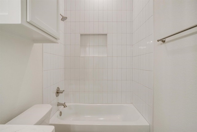 bathroom with toilet and tiled shower / bath