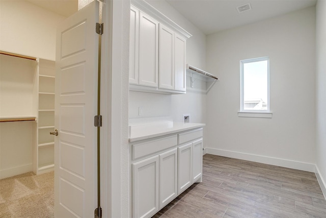 clothes washing area with light hardwood / wood-style floors, cabinets, and hookup for a washing machine