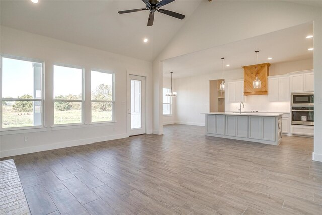 kitchen with sink, a center island with sink, black appliances, and white cabinetry