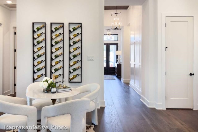 hall with dark wood-type flooring, a chandelier, and french doors