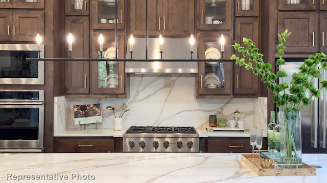 kitchen with stainless steel appliances, light stone countertops, and backsplash