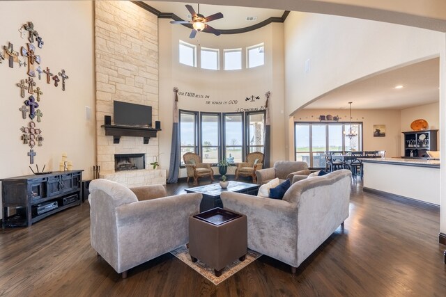 living room featuring crown molding, a stone fireplace, and dark hardwood / wood-style flooring