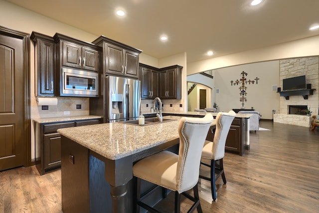 kitchen with an island with sink, dark hardwood / wood-style flooring, appliances with stainless steel finishes, and tasteful backsplash