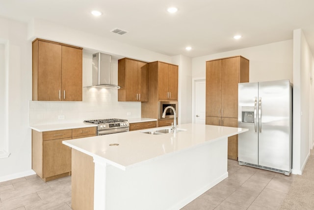 kitchen with stainless steel appliances, tasteful backsplash, visible vents, a sink, and wall chimney range hood