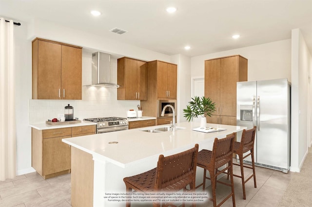 kitchen featuring visible vents, backsplash, appliances with stainless steel finishes, a sink, and wall chimney range hood