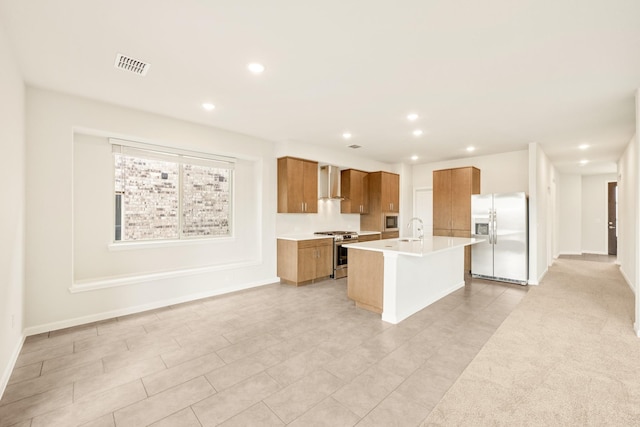 kitchen with a sink, visible vents, appliances with stainless steel finishes, wall chimney exhaust hood, and brown cabinetry