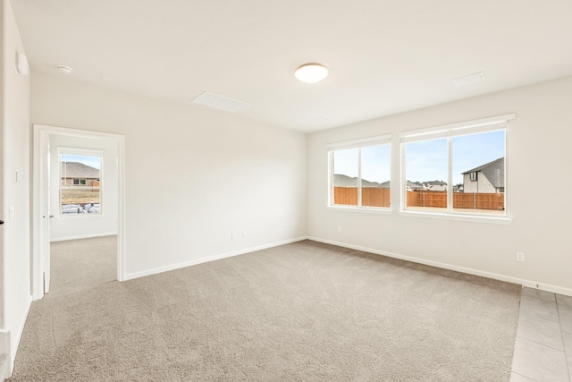 carpeted empty room with plenty of natural light, tile patterned floors, and baseboards