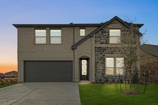 view of front of house featuring a garage, driveway, a lawn, and brick siding