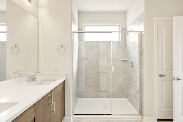 bathroom with a sink, a shower stall, and double vanity