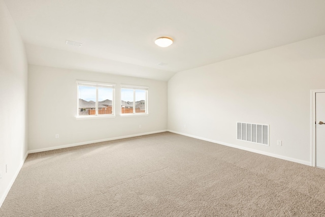 spare room featuring carpet, visible vents, lofted ceiling, and baseboards