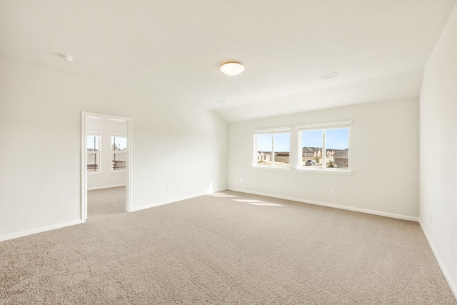 carpeted empty room featuring lofted ceiling, visible vents, and baseboards