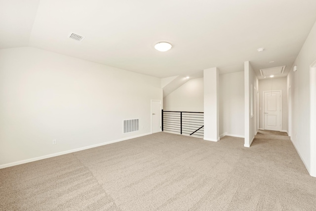 spare room featuring light carpet, attic access, visible vents, and lofted ceiling