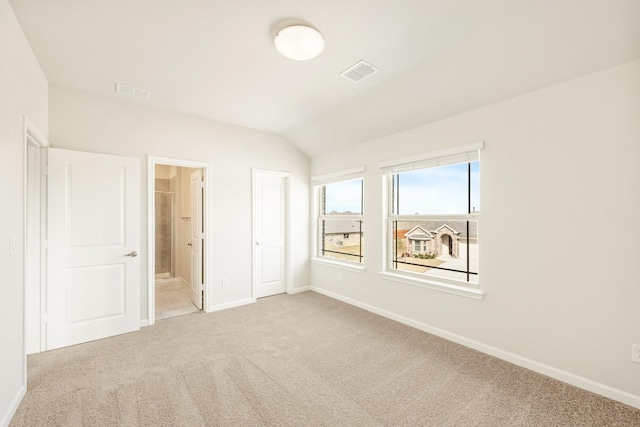 unfurnished bedroom featuring baseboards, visible vents, connected bathroom, vaulted ceiling, and carpet flooring