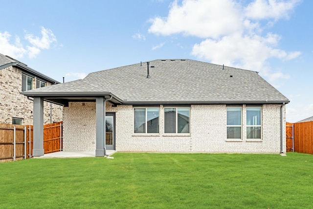 rear view of property featuring a shingled roof, a patio area, a fenced backyard, and a yard