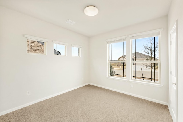 empty room featuring light carpet, visible vents, and baseboards